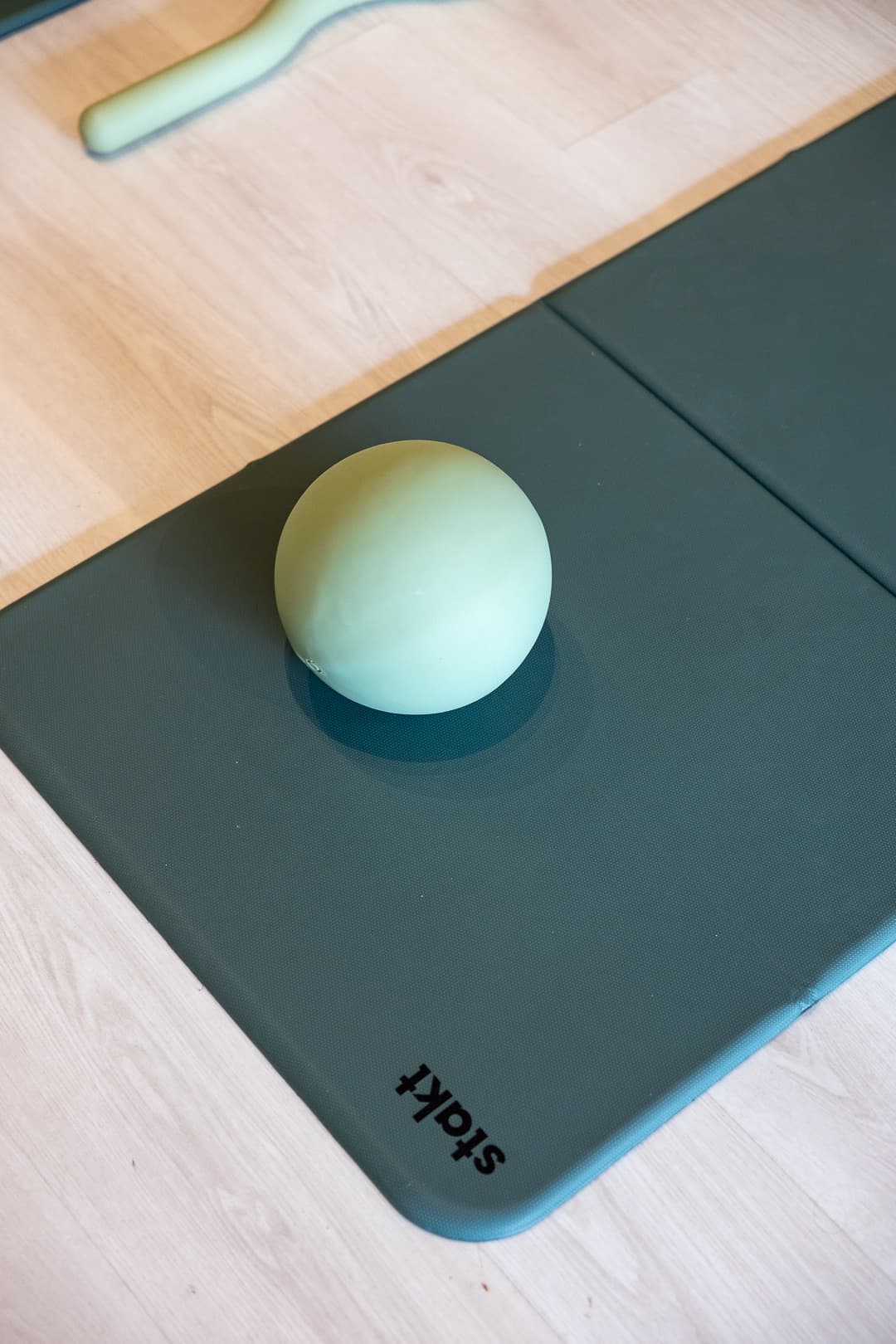 A sage pilates ball resting on a folded mat